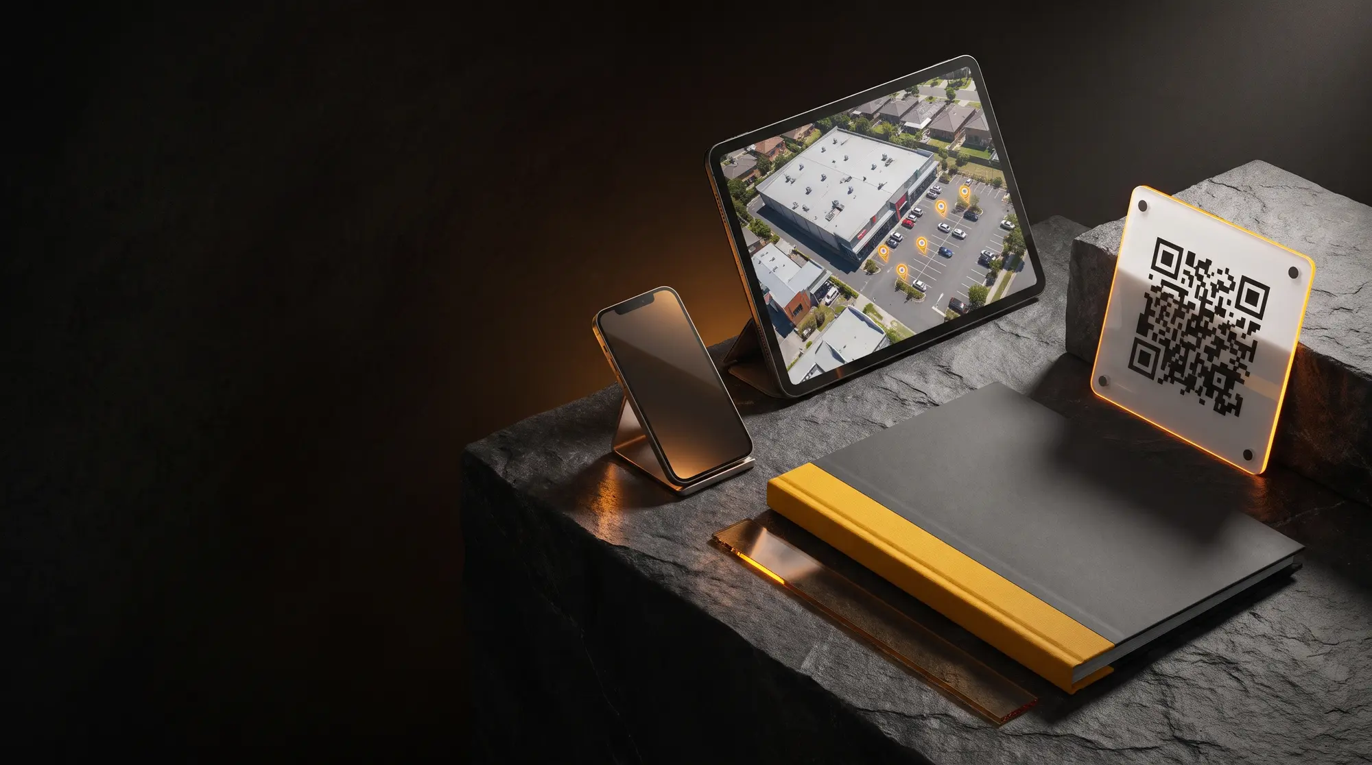 The compliance kit: printed pack with amber spine, QR sighting sign, phone and tablet showing a site's aerial station map